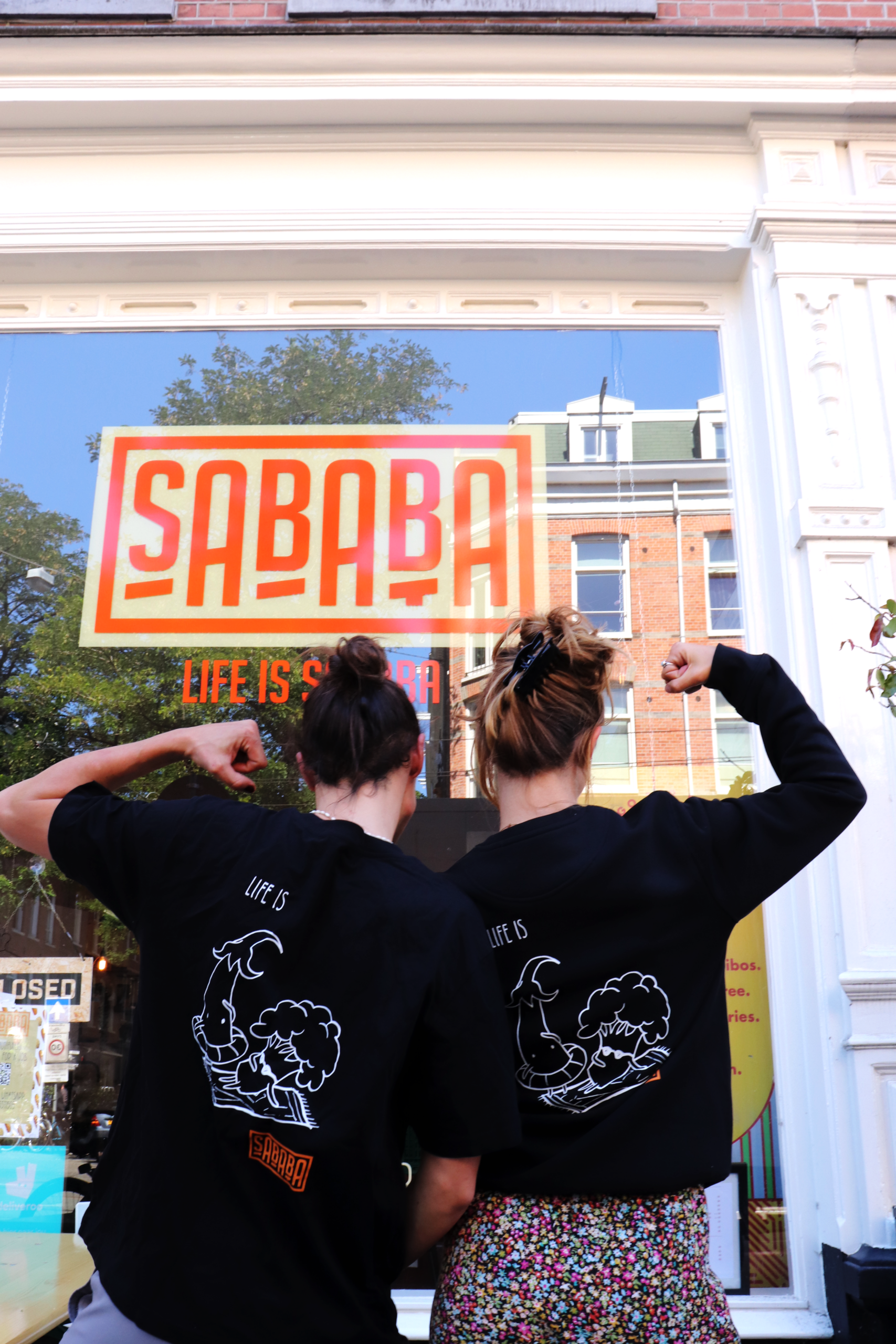 Twee teamleden in Sababa-shirts voor de winkel